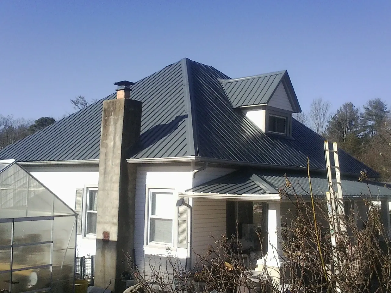 Dark blue standing seam metal roof on a white farmhouse with dormer — Slate & Tile Roof Repair by Roofing Brothers in Darby