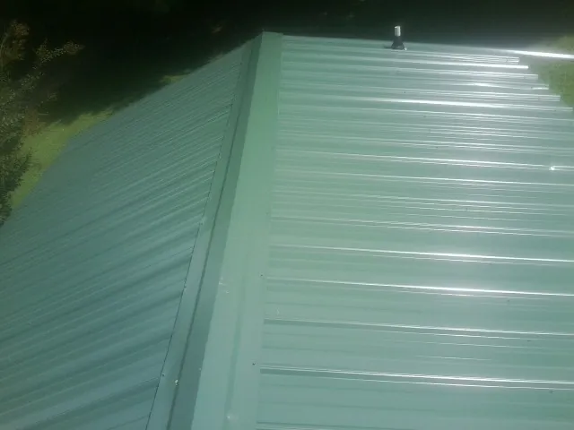 New green metal panels meeting at the ridge of a roof — Flat Roof Repair work by our crew in Darby