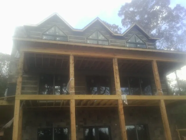 Dormers and porch framing on a large log home under construction — Roof Coating work by our crew in Darby