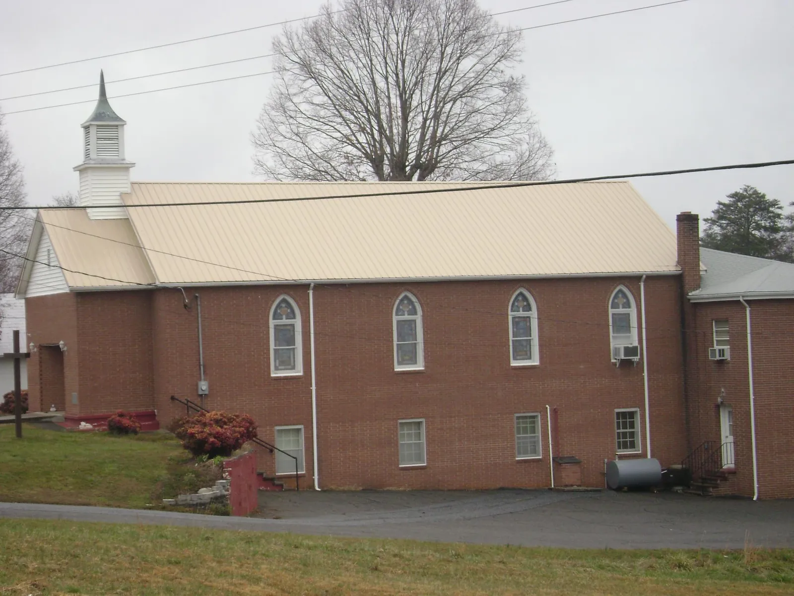 New tan metal roof on a brick church with a white steeple in Darby